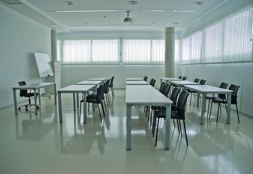 A clean, modern conference room with arranged desks, chairs, and a whiteboard.